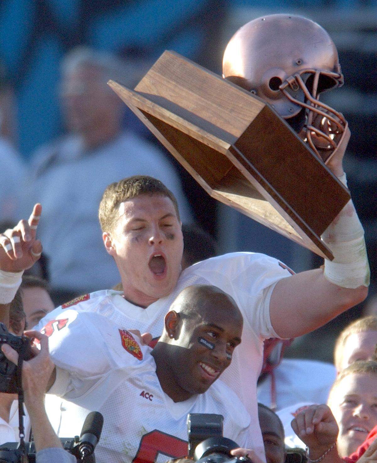 N.C. State’s Philip Rivers and Rod Johnson celebrate with Rivers’ MVP trophy after the Gator Bowl at Alltel Stadium in Jacksonville, Florida on Jan 1, 2003. The Wolfpack beat the Irish 28-6. Rivers was named the MVP of the Bowl. Johnson had two interceptions in the game.
