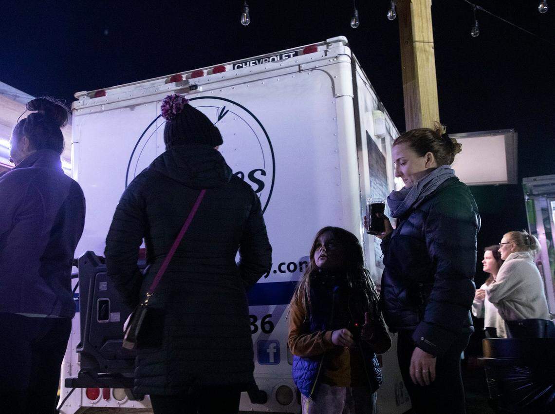 Elowyn Hoelscher, 7, stands in line at a food truck with her mother, Erika Hoelscher, at Red’s Corner during the Moore County power outage on Monday, Dec. 5, 2022, in Southern Pines, N.C.