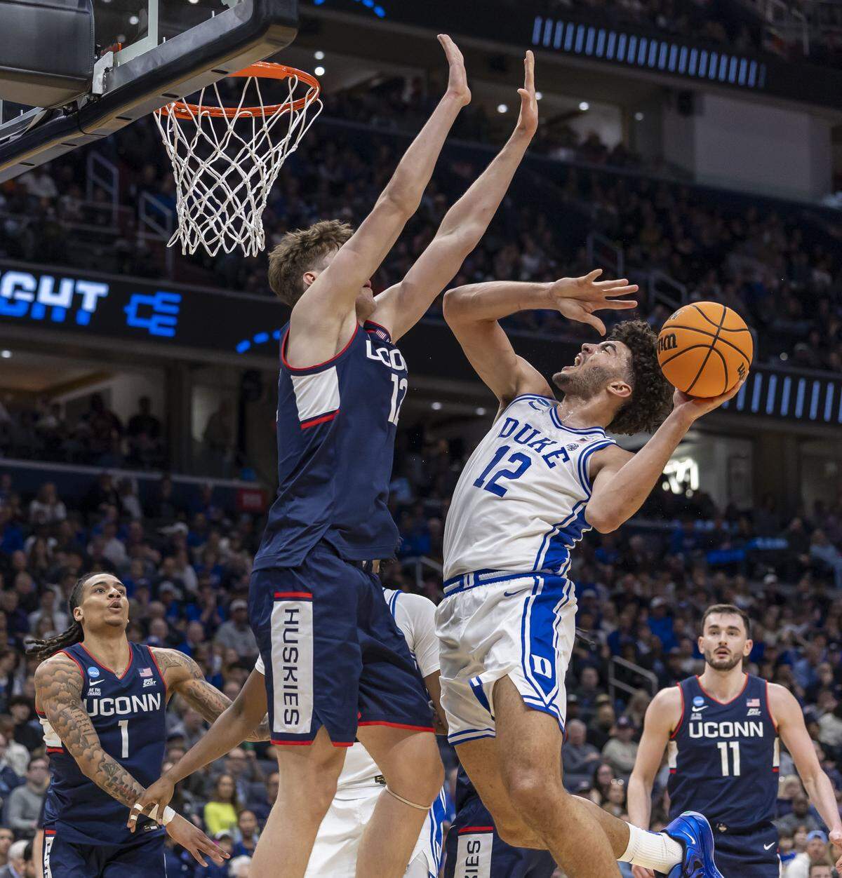 Connecticut center Eric Reibe (12) defends Duke forward Cameron Boozer (12) in the first half on Sunday, March 29, 2026, in the NCAA East Regional Championship, at Capital One Arena in Washington, D.C.