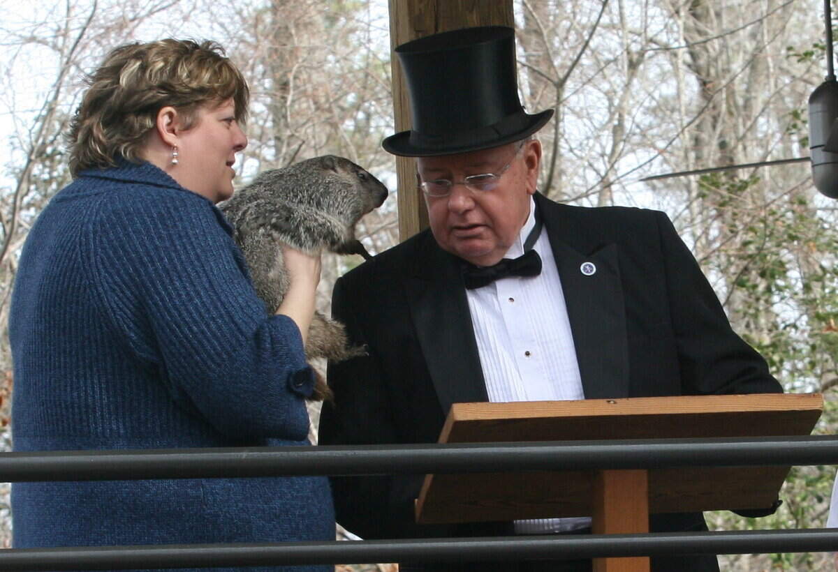 Stephanie Shaffer, park manager, holds groundhog weather prognosticator Mortimer as he whispers his forecast to Garner Mayor Ronnie Williams.
