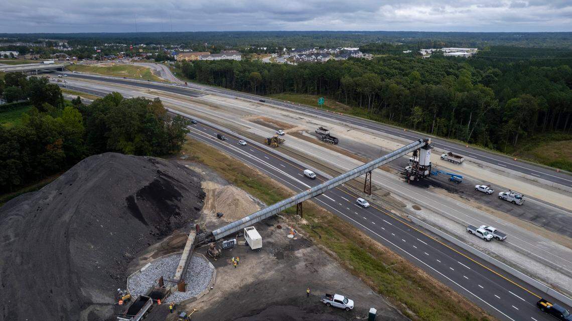 A conveyor system carries asphalt over the eastbound lanes of I-40 near the N.C. 42 interchange in Garner on Wednesday, Sept. 27, 2023. The conveyor will move about 175,000 tons of asphalt from its plant off Cleveland Road in the coming months, enough to pave 5 miles of eight-lane highway.