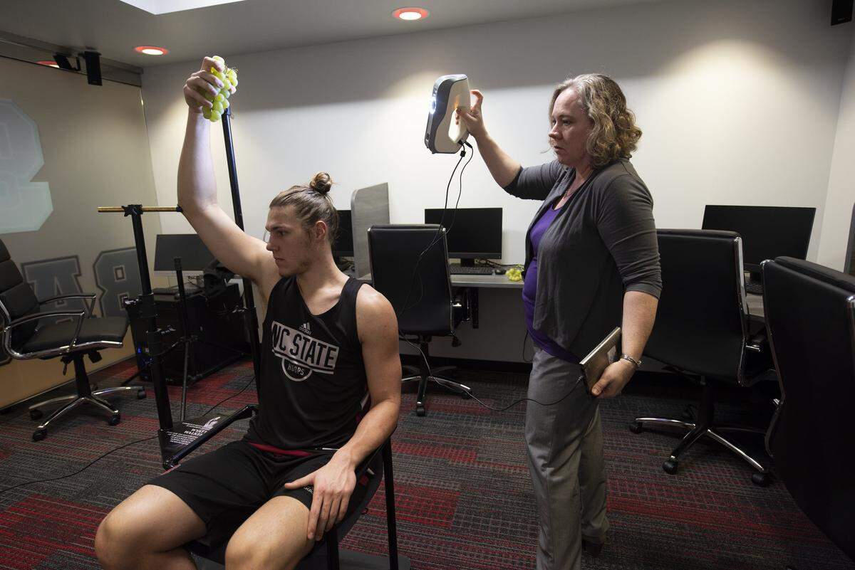 North Carolina State University basketball player Wyatt Walker models with a bunch of grapes at the team’s Dail Basketball Center practice facility in Raleigh as part of a restoration project for the Statue of Bacchus.
