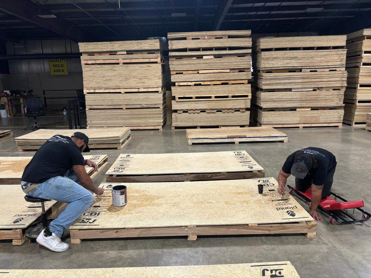 Plantd employees in Oxford, NC paint logos on the startup’s grass-made wood panels.