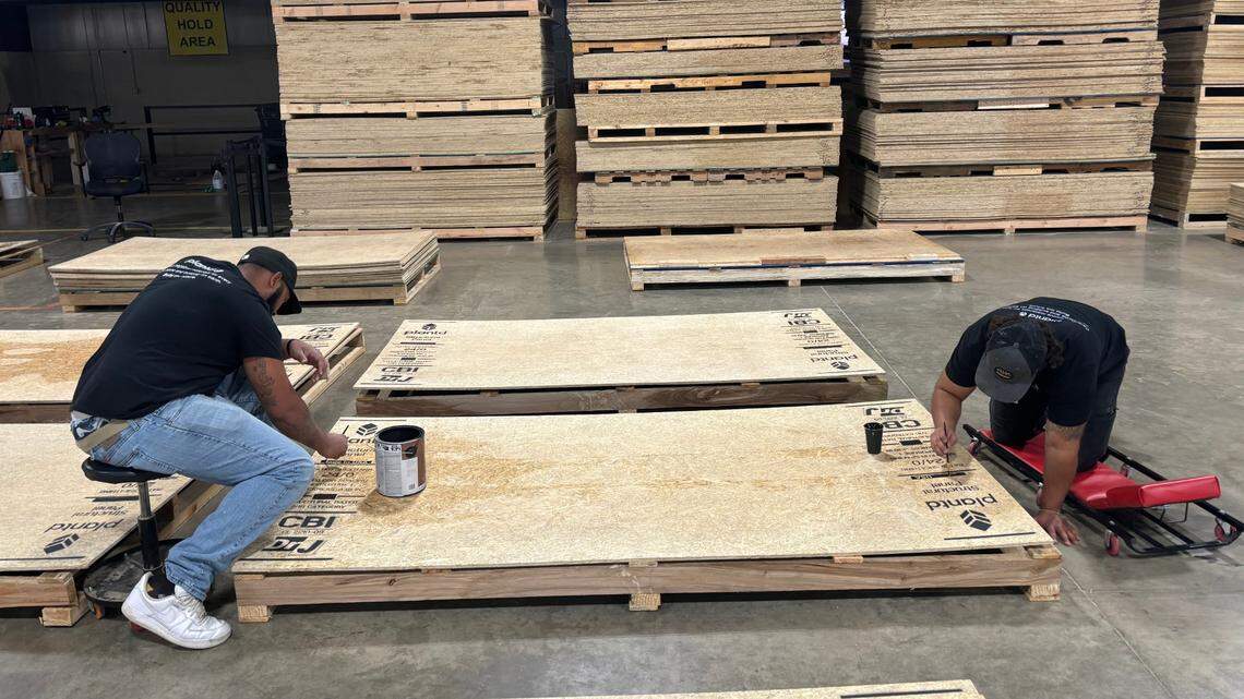 Plantd employees in Oxford, NC paint logos on the startup’s grass-made wood panels on Oct. 16, 2024. . 