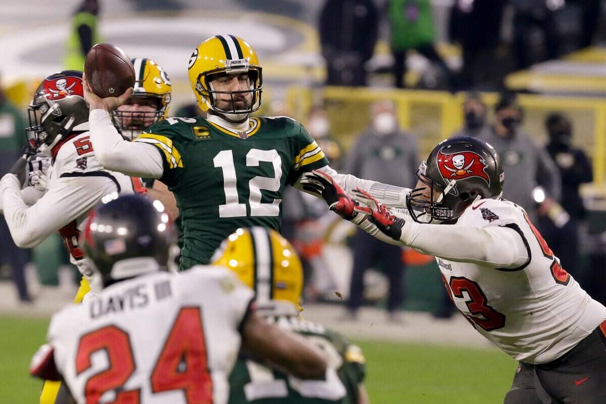 Green Bay Packers quarterback Aaron Rodgers (12) evades a tackle as he looks to pass against the Tampa Bay Buccaneers during the second half of the NFC championship NFL football game in Green Bay, Wis., Sunday, Jan. 24, 2021.