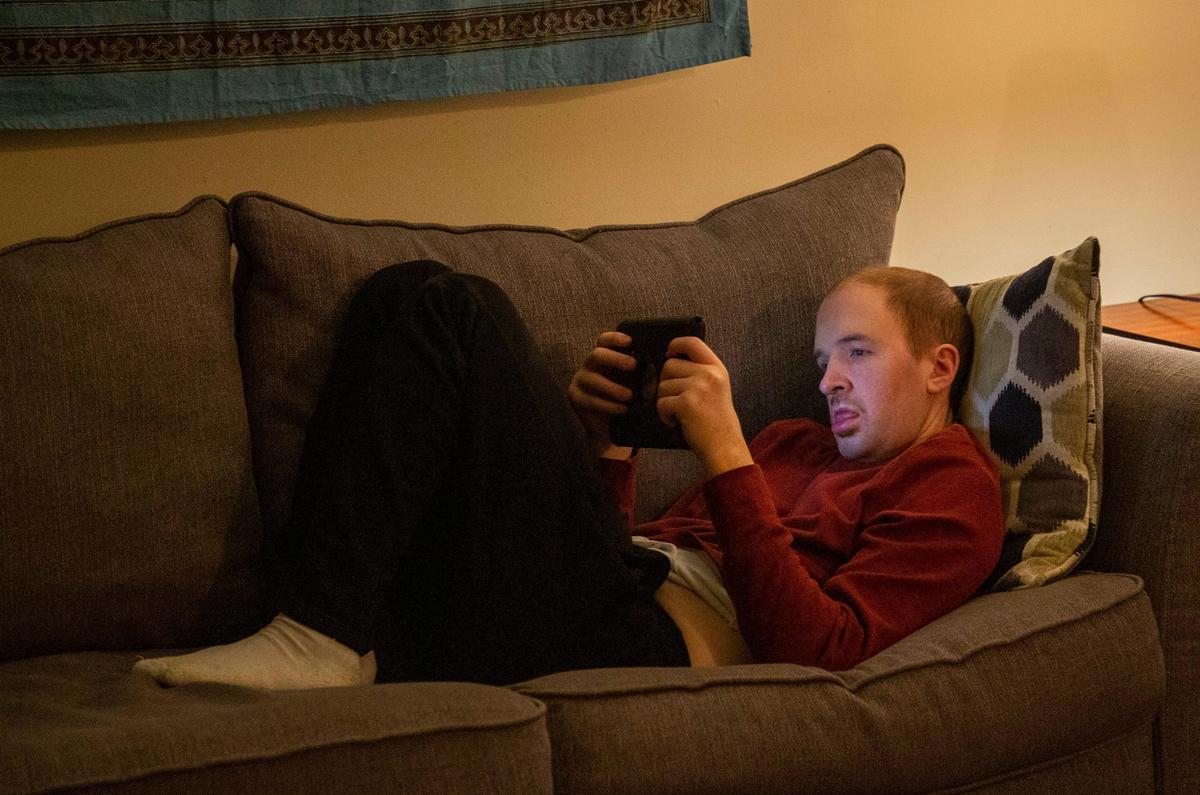 Dylan Hoyle, 29, watches a movie on a tablet in his own home, which he has lived in despite a diagnosis of severe autism since 2017, with 24-hour one-to-one staff support funded by a Medicaid waiver, on Thursday, Nov. 11, 2019, in Chapel Hill, NC.