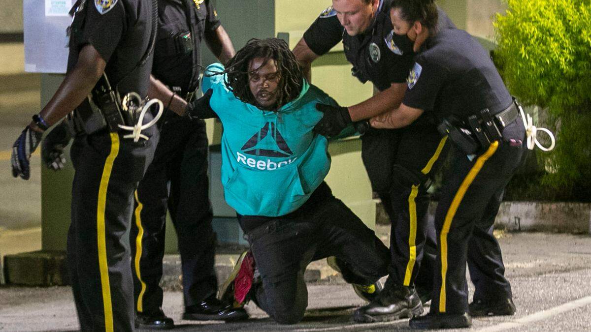 Elizabeth City Police arrest a demonstrator in the municipal building parking after 11 p.m. on Wednesday, April 28, 2021 in Elizabeth City, N.C. Five people were arrested for violating the 8 p.m. curfew, one week after Andrew Brown Jr.’s death at the hands of Pasquotank County deputies.