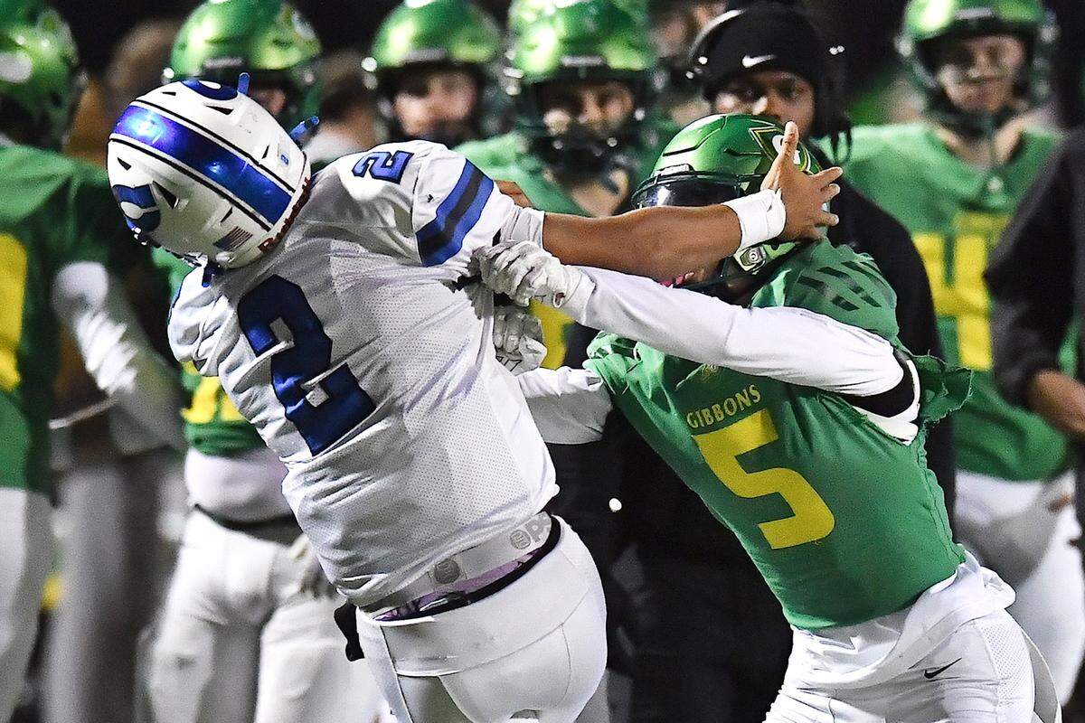 Cardinal Gibbons' Hudson VanDyke (5) pushes Clayton quarterback Aiden Smalls (2) out of bounds during the second half. The Clayton Comets and the Cardinal Gibbons Crusaders met in the East Regional Final of the NCHSAA 7A Football Championship in Clayton, N.C. on December 4, 2025.