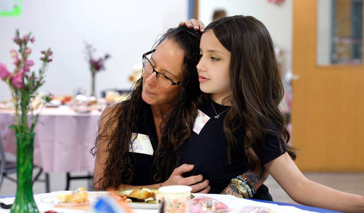 Jill Hurt hugs her daughter Addison, 9, during a Mother’s Day tea at Healing Transitions in Raleigh, N.C., Saturday, May 10, 2025. Healing Transitions is a place for recovery of all addictions. The tea was organized by Hurt and participant Lela Brantley, both of whom are recovering from alcohol addiction.
