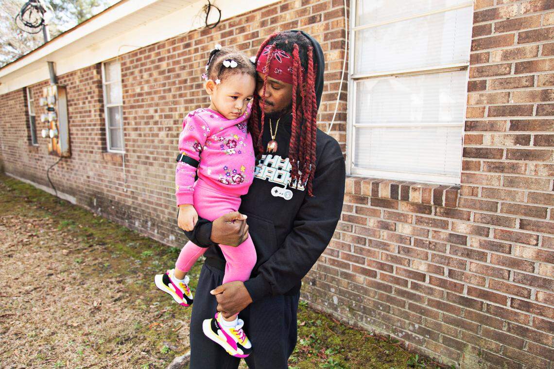 Sedriq Crandell, right, nuzzles his two-year-old daughter, Emerald, outside of their Rocky Mount home on Thursday, March 3, 2022. Crandell, who worked at QVC for four years and escaped the fire along with several co-workers, has not been able to find a comparable job since the fire.