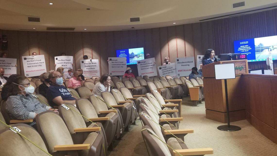 People hold signs during a June 7, 2022, Raleigh City Council meeting.