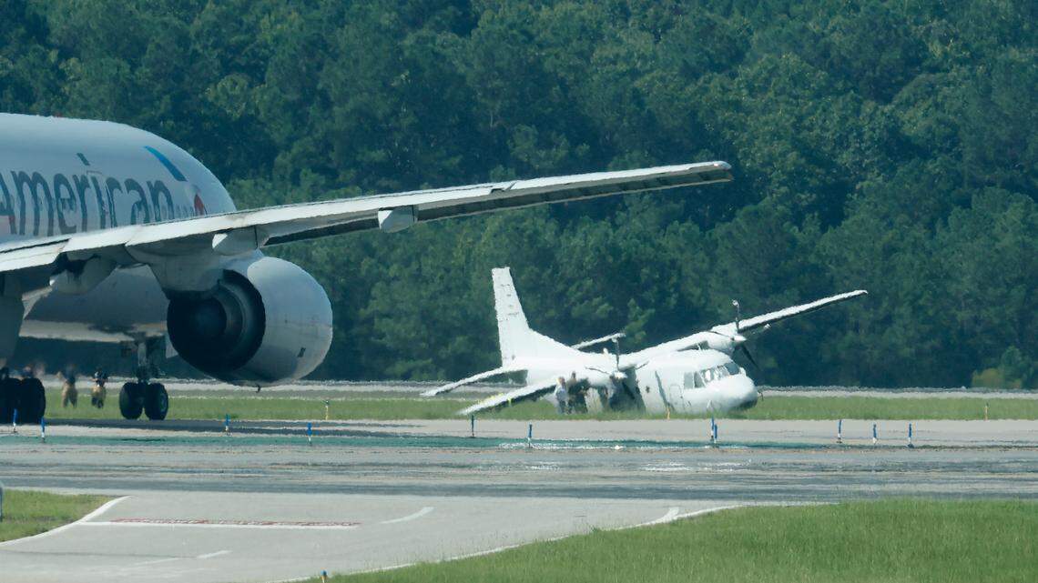 A twin-engine turbo prop aircraft sits on the grass near runway 5R-23L at Raleigh-Durham International Airport Saturday July 30, 2022. The plane made an emergency landing at RDU Friday after reporting landing gear issues.