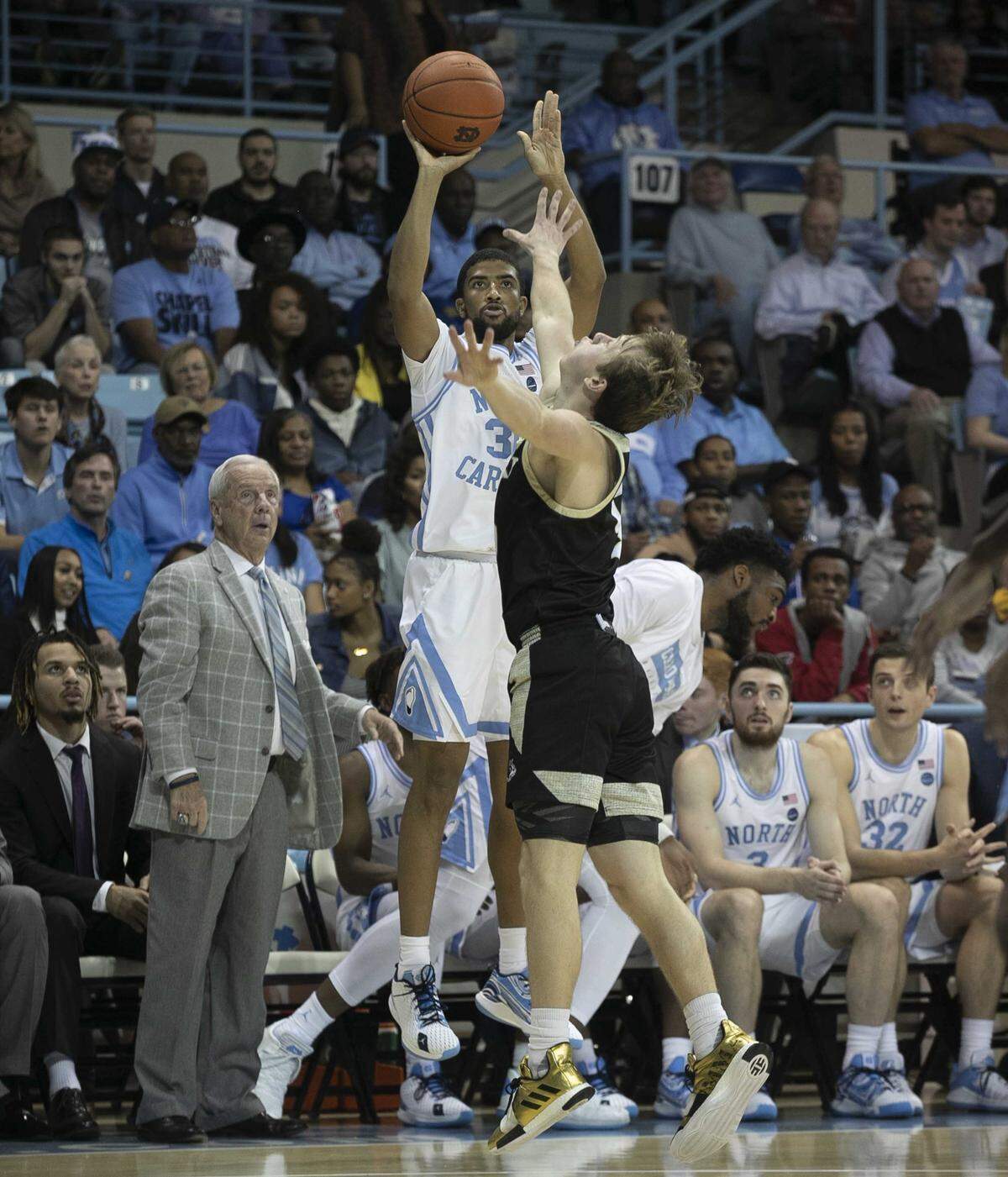 North Carolina’s K.J. Smith (30) launches a three point attempt in front of coach Roy Williams during the second half against Wofford on Sunday, December 15, 2019 at Carmichael Arena in Chapel Hill, N.C.