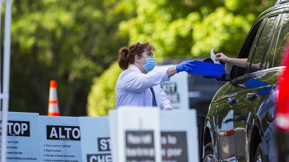 A completed coronavirus test is transferred through the car window at a free drive-through testing site administered by Walgreens across the street from their Guess Road location in Durham, N.C., on Friday, May 15, 2020.