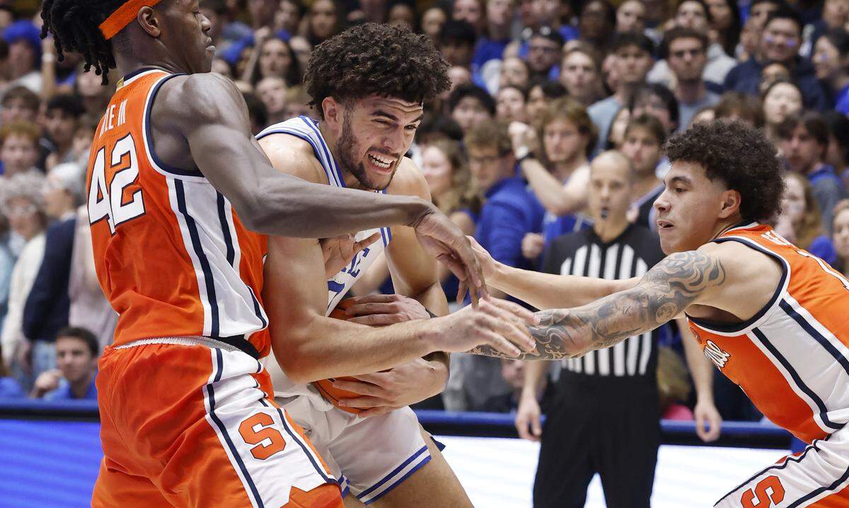 Duke’s Cameron Boozer (12) drives between Syracuse's William Kyle III (42) and Naithan George (11) during the first half of Duke’s game against Syracuse at Cameron Indoor Stadium in Durham, N.C., Monday, Feb. 16, 2026.