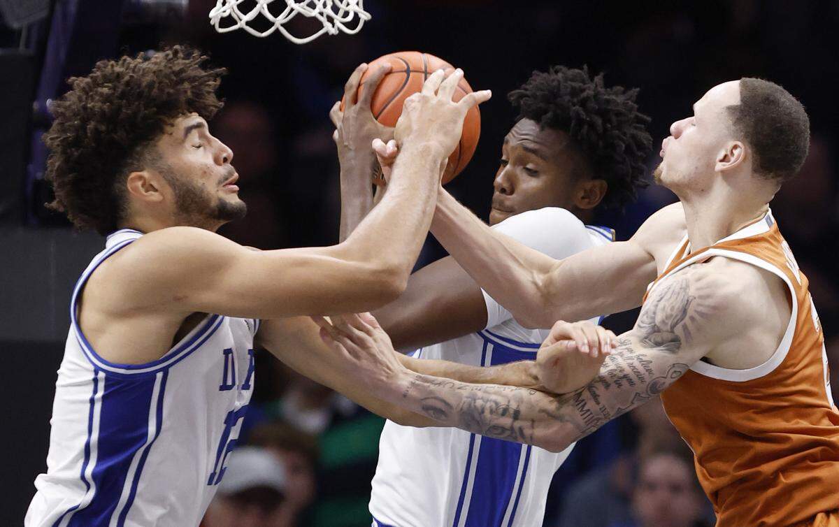 Duke’s Patrick Ngongba (21) pulls in a rebound from Texas' Chendall Weaver (2) as Cameron Boozer (12) assists during the second half of Duke’s 75-60 victory over Texas in the Dick Vitale Invitational at the Spectrum Center in Charlotte, N.C., Tuesday, Nov. 4, 2025. 