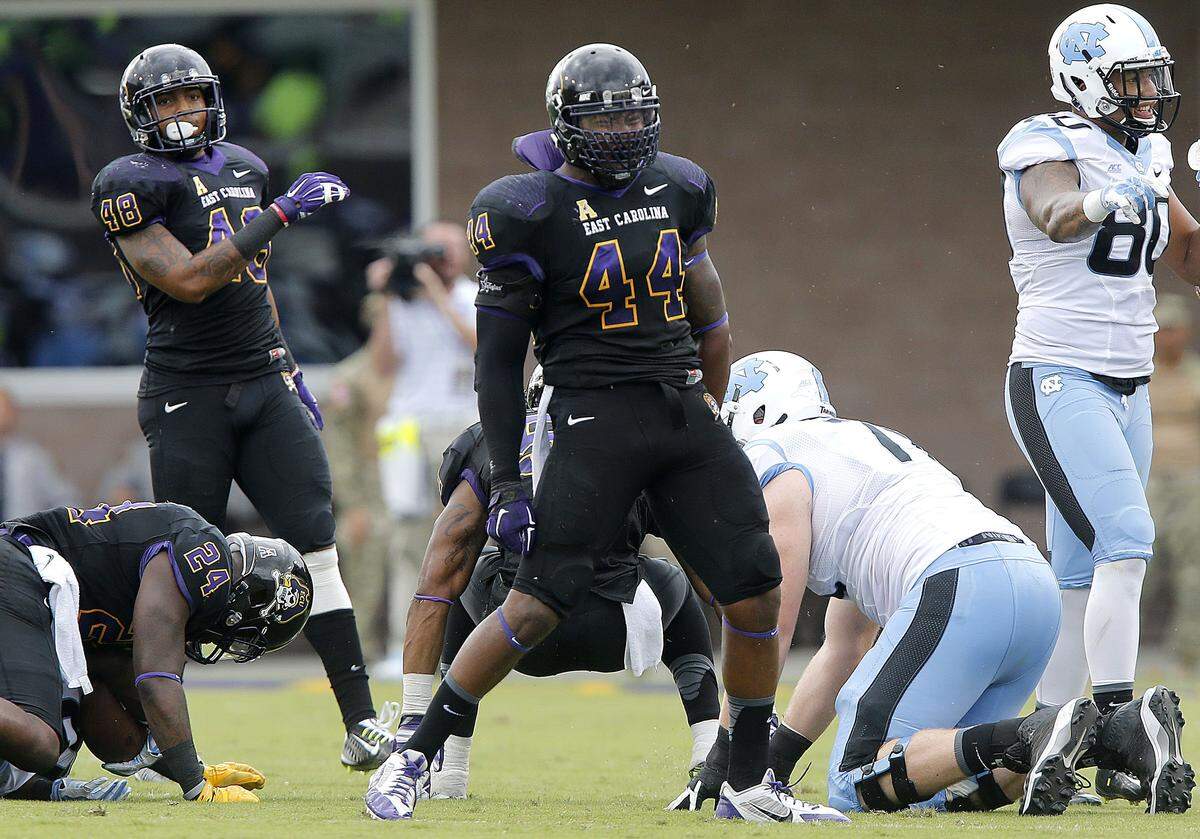 East Carolina linebacker Zeek Bigger, middle, celebrates after stopping North Carolina’s Romar Morris, not shown, during the Pirates 70-41 over the Tar Heels on Sept. 20, 2014.