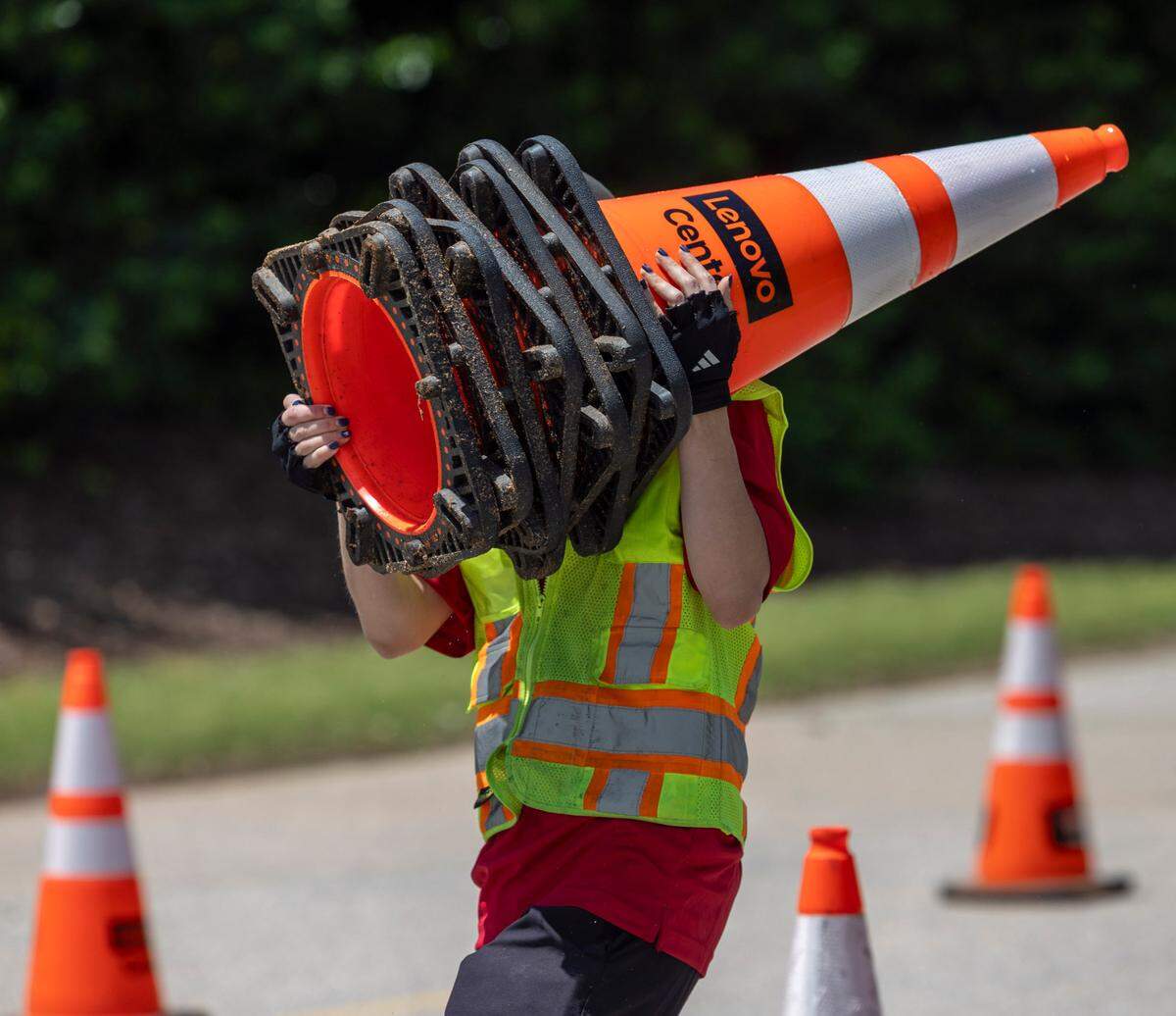 Simon Cassidy carries a stack of traffic cones as they are placed along Westchase Blvd. in preparation for the Linkin Park concert on Tuesday, May 6, 2025 at Lenovo Center in Raleigh, N.C. Lenovo Center employees place more than 2000 cones directing traffic to parking spots and exits for each event at the arena.