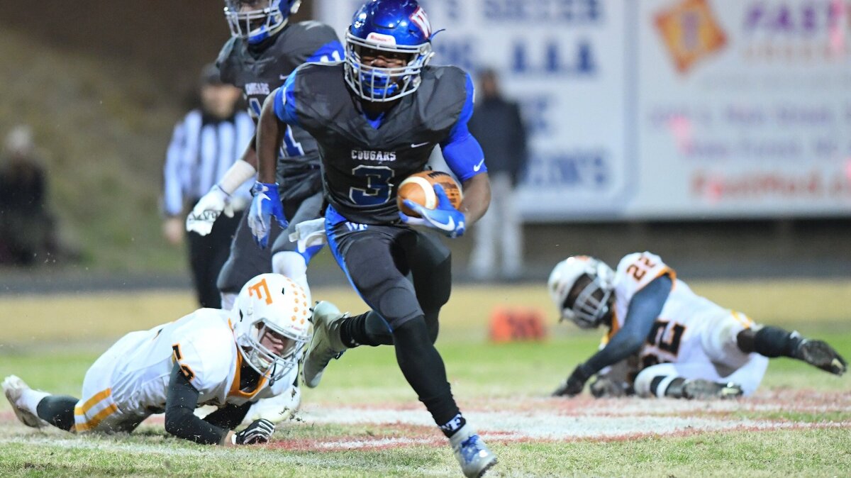 Maquel Haywood (3) of Wake Forest moves the ball against Cole Everett, left, and Emmanuel Muteberwa (22) of Fuquay-Varina. The Fuquay-Varina Bengals visited the Wake Forest Cougars in a high school football game on November 23, 2018. Wake Forest won 55-7.