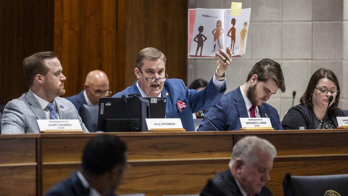 N.C. House Majority Leader Brenden Jones holds up the book “It Isn't Rude to Be Nude” by Rosie Haine while questioning Chapel Hill-Carrboro City Schools Superintendent Rodney Trice and School Board Chair George Griffin during a sometimes tense House committee hearing on Wednesday, Dec. 10, 2025, in the Legislative Building auditorium in Raleigh. During the hearing, Jones cited and tossed several children’s books from a third-party list that had previously appeared on the district’s website.
