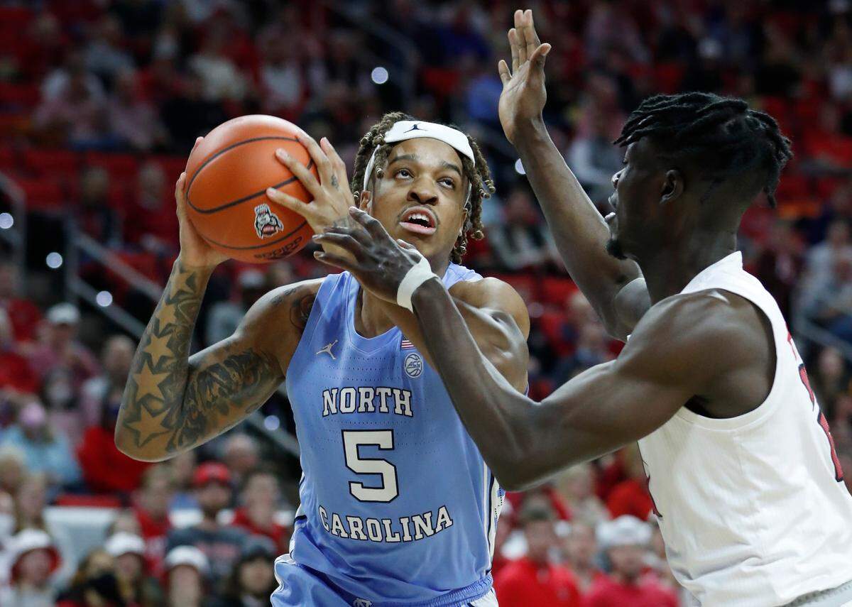 North Carolina’s Armando Bacot (5) heads to the basket as N.C. State’s Ebenezer Dowuona (21) defends during the first half of N.C. State’s game against UNC at PNC Arena in Raleigh, N.C., Saturday, Feb. 26, 2022.