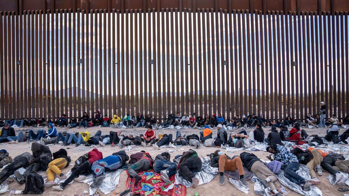 Migrants and asylum seekers wait to be picked up and processed by U.S. Border Patrol agents in Organ Pipe Cactus National Monument along the U.S.-Mexico border about a mile west of Lukeville, Ariz., on Dec. 4, 2023. The Lukeville Port of Entry was closed indefinitely by officials on Dec. 4.
