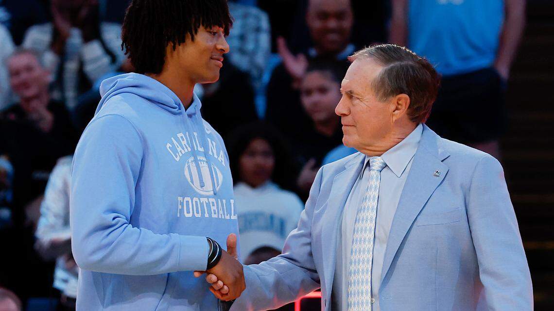 North Carolina football recruit Bryce Baker shakes hands with recently hired football coach Bill Belichick as they are introduced during halftime of the Tar Heels’ men’s basketball game against La Salle on Saturday, Dec. 14, 2024, at the Smith Center in Chapel Hill, N.C.