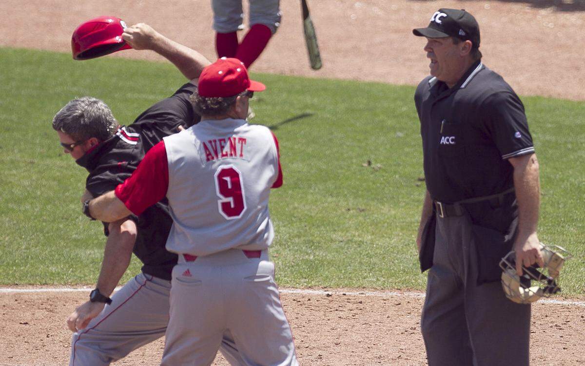N.C. State coach Elliott Avent restrains assistant coach Chris Hart (21) after they argued with umpire Mark Chapman after Chapman called Trea Turner out at home plate in the ACC Baseball Championship play-in game at NewBridge Bank Park in Greensboro in 2014.