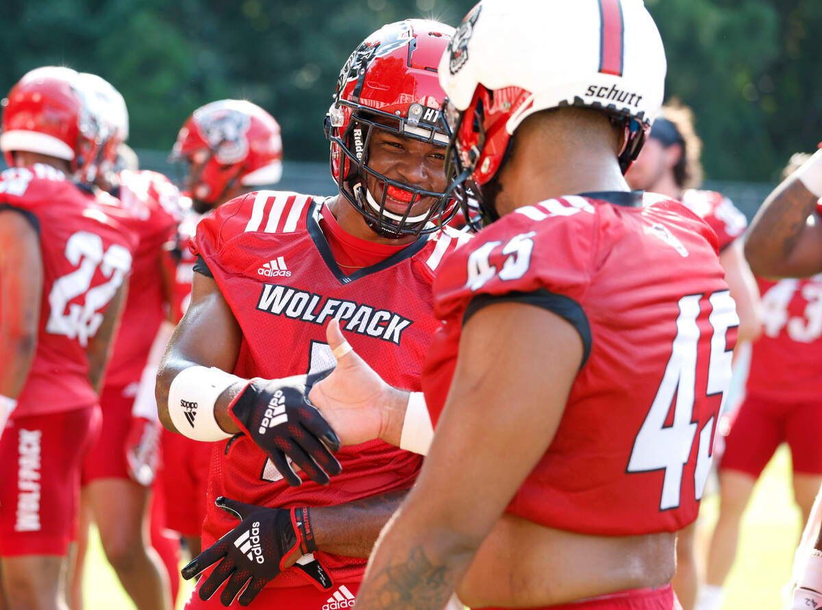 N.C. State’s Isaiah Moore (1) smile as he greets Davin Vann (45) during N.C. State football’s first practice of fall camp in Raleigh, N.C., Wednesday, August 3, 2022.