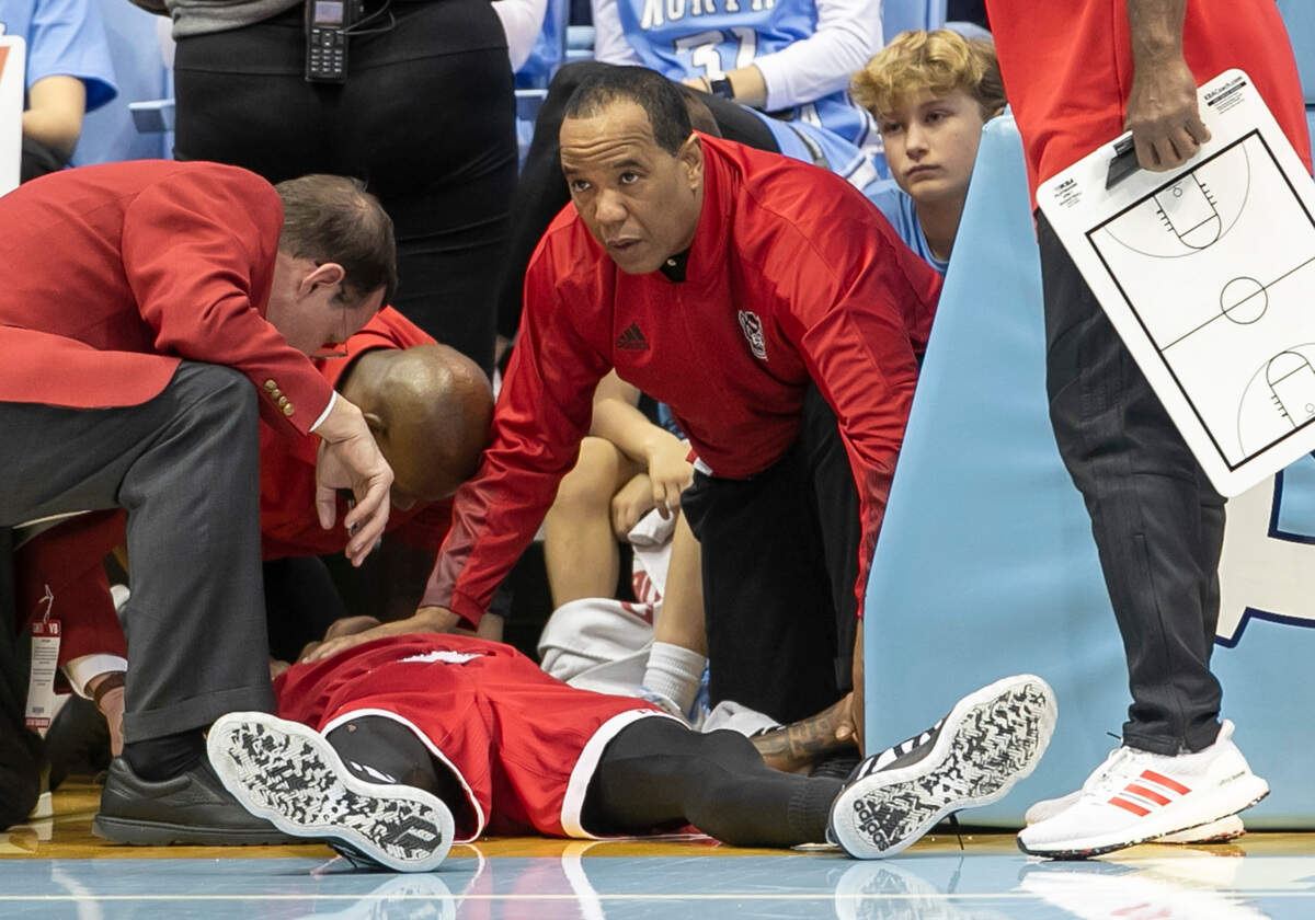 N.C. State coach Kevin Keatts attends to N.C. State’s Terquavion Smith (0) after falling on a hard foul by North Carolina’s Leaky Black in the second half. Smith was taken to the hospital and Black was ejected from the game on Saturday, January 21, 2023 at the Smith Center in Chapel Hill, N.C.