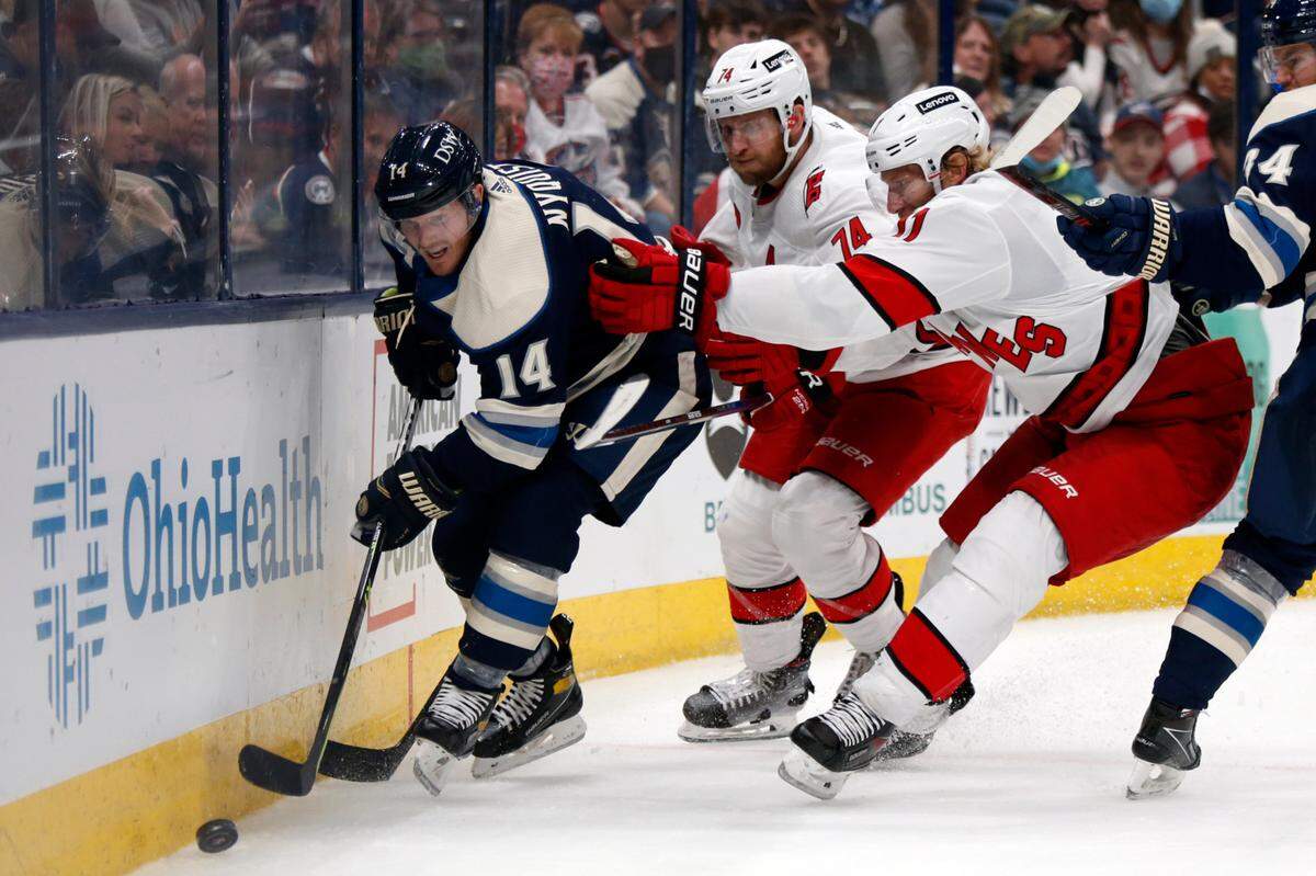 Carolina Hurricanes defenseman Jaccob Slavin, center, and forward Jordan Staal pressure Columbus Blue Jackets forward Gustav Nyquist, left, in NHL game in Columbus, Ohio, Oct. 23, 2021. (AP Photo/Paul Vernon)