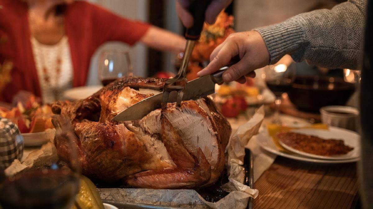 Pictured is a person slicing a roasted on a table for Thanksgiving dinner,