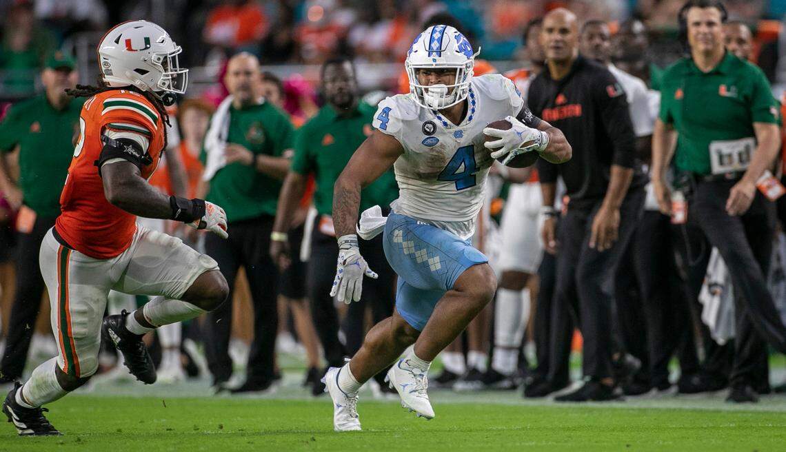 North Carolina’s Caleb Hood (4) looks for running room against Miami’s Jahfari Harvey (12) after a pass completion from quarterback Drake Maye in the fourth quarter on Saturday, October 8, 2022 at Hard Rock Stadium in Miami Gardens, Florida.