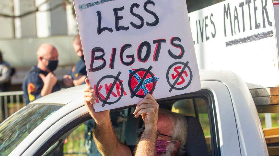 A counter-protester holds up a sign while driving his pickup truck past a rally in support of President Donald Trump that included members of the Proud Boys Saturday, Nov. 28, 2020.