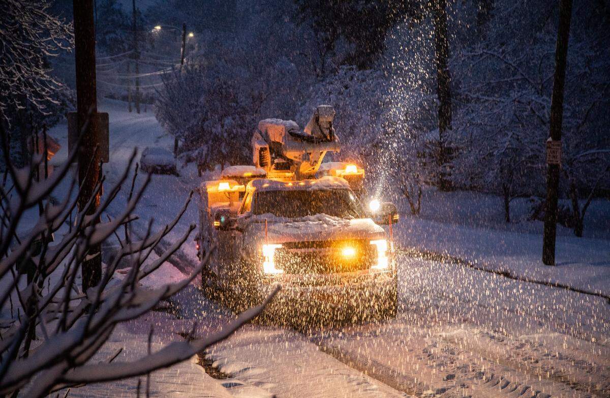 A Duke Energy crew works to restore power on Rumson Road in Raleigh as snow continues to fall Sunday morning, Dec. 9, 2018.