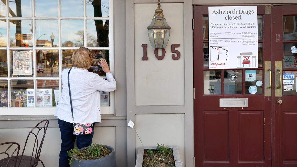 Marianne Harward of Cary takes photos of the inside of Ashworth Drugs in downtown Cary Thursday, Feb. 8, 2024. After 67 years of filling prescriptions and hot dog and orangeade orders, the store on West Chatham Street closed its doors. Harward, who has been going to Ashworth ‘forever’ said of the closing, “I didn’t believe it because I thought it would never close.”
