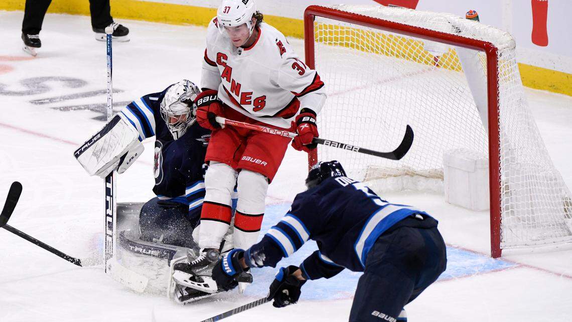 Winnipeg Jets goaltender Connor Hellebuyck (37) makes as save as Carolina Hurricanes’ Andrei Svechnikov (37) looks for the rebound during the third period of an NHL hockey game Tuesday, Dec. 7, 2021, in Winnipeg, Manitoba. (Fred Greenslade/The Canadian Press via AP)