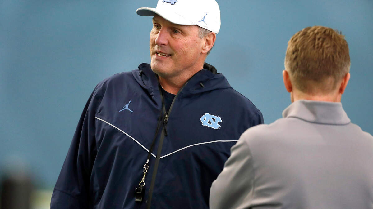 North Carolina assistant head coach Tim Brewster passes by UNC interim chancellor Kevin Guskiewicz during UNC’s first spring football practice in Chapel Hill, N.C., Sunday, March 3, 2019.