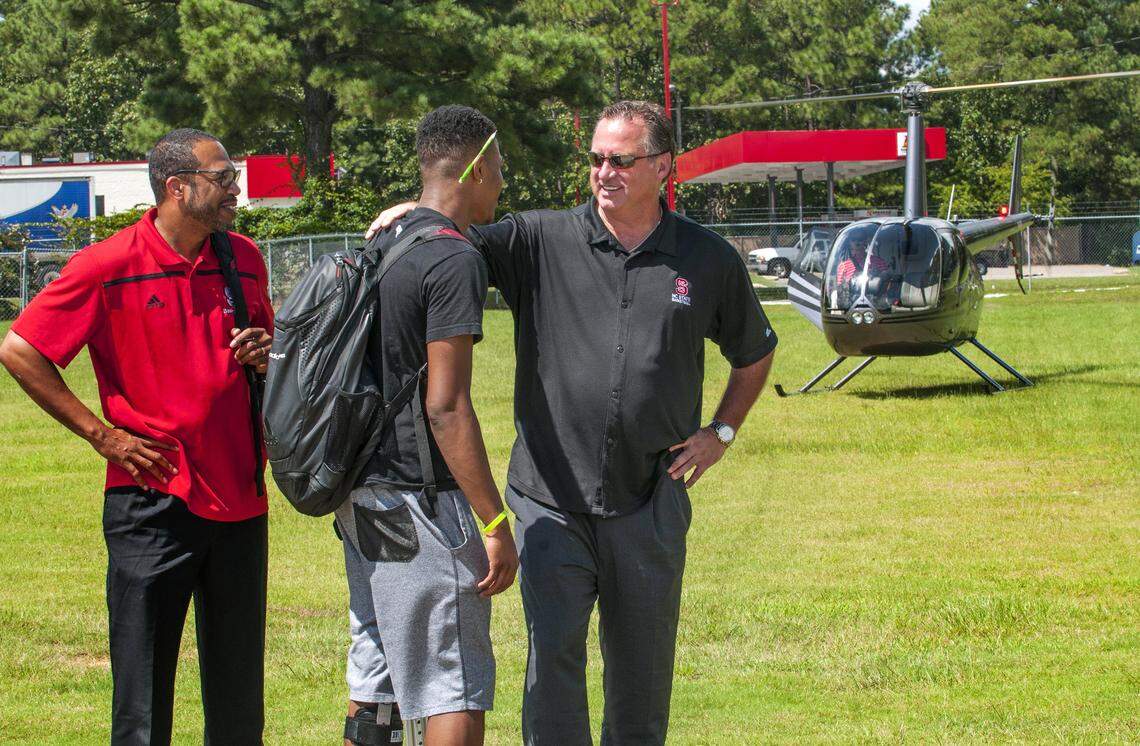 Dennis Smith Jr., center,  greets N.C. State assistant coach Orlando Early, left, and coach Mark Gottfried after they arrived by helicopter at Trinity Christian School on Wednesday, Sept. 9, 2015.