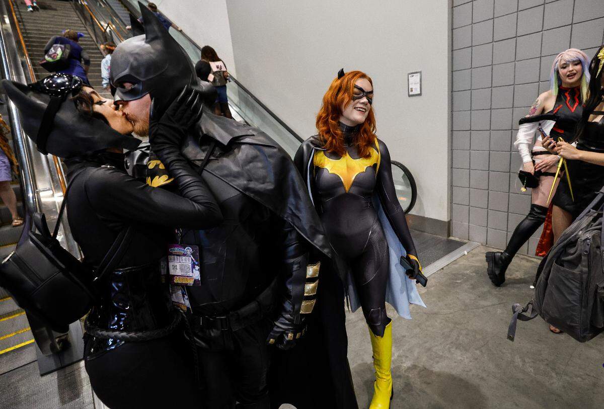 Rain Morales and her husband Justice Vick of Smithfield attend GalaxyCon Raleigh at the Raleigh Convention Center Sunday, July 28, 2024. Morales is dressed as Catwoman and Vick is Batman. Behind them is Grace Marie of Raleigh dressed as Batgirl.