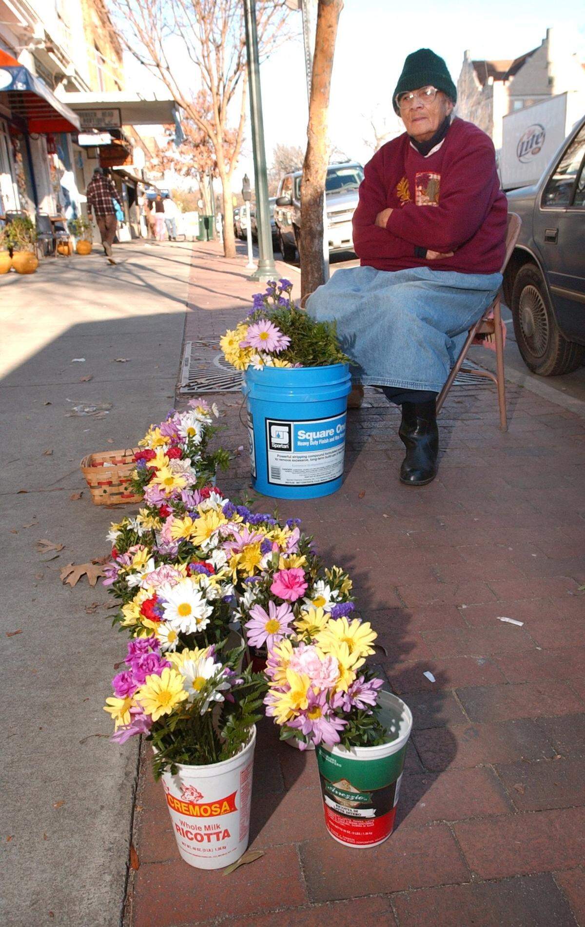 Millie Pratt endures the cold winds of winter to sell signs of spring, in this case carnations and a variety of daisies, from her perch on the sidewalks of E. Franklin Street in downtown Chapel Hill on Wednesday, Jan. 25, 2006. Flower ladies were more common in Chapel Hill in past decades. Pratt has been selling flowers off and on since the late 1950s.
