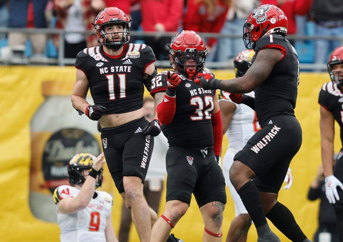 N.C. State linebacker Isaiah Moore (1) celebrates with linebacker Drake Thomas (32) after Thomas sacked Maryland quarterback Billy Edwards Jr. (9) during the first half of N.C. State’s game against Maryland in the Duke’s Mayo Bowl at Bank of America Stadium in Charlotte, N.C., Friday, Dec. 30, 2022. N.C. State linebacker Payton Wilson (11) is to the left.