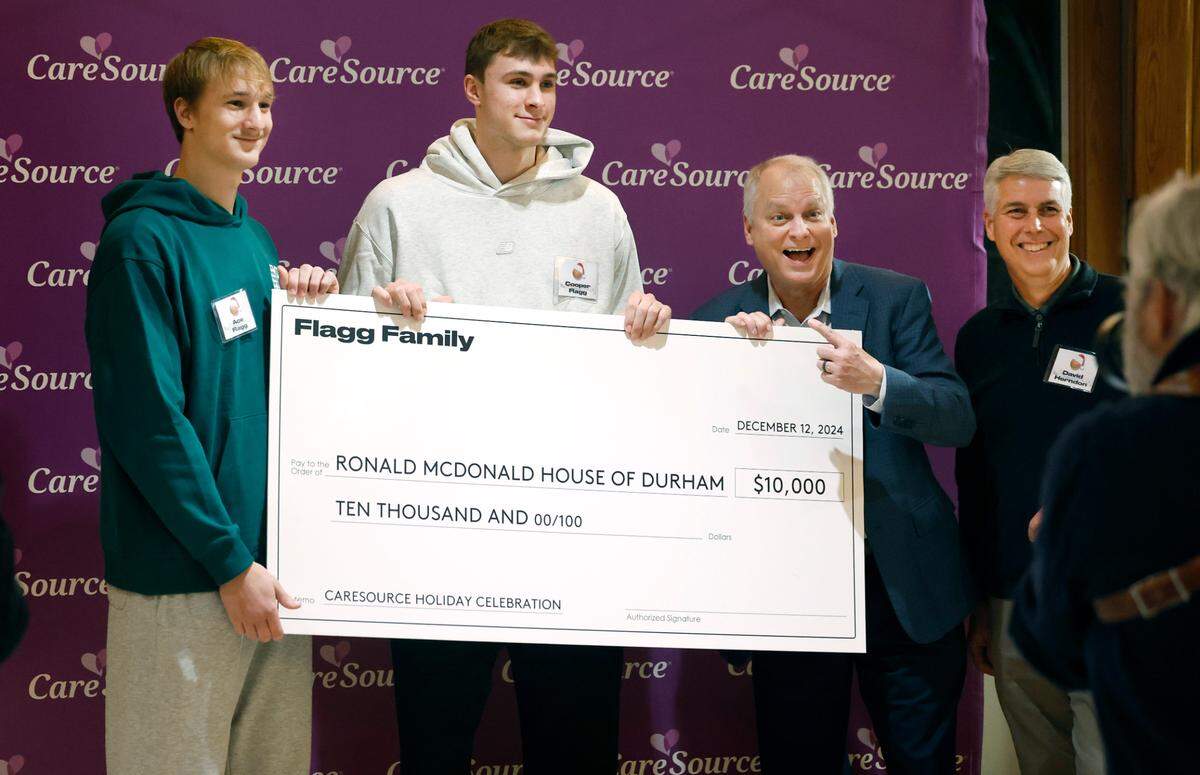Cooper and Ace Flagg pose with a $10,000 check the Flagg family donated to Ronald McDonald House Charities of the Triangle during a gathering at RMH of Durham on Thursday, Dec. 12, 2024. With the Flagg brothers are Oie Osterkamp, Chief Executive Officer of Ronald McDonald Charities of the Triangle, center right, and David Herndon, president of the North Carolina market of CareSource, right.