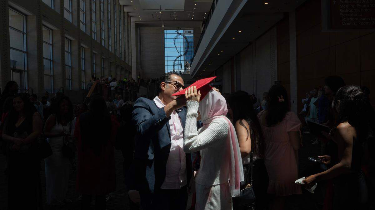 Hana Elsalakawi’s father fits a graduation cap on her head as they walk out of her brother Adham’s graduation ceremony from Middle Creek High School on Wednesday, June 18, 2025 at the Raleigh Convention Center.