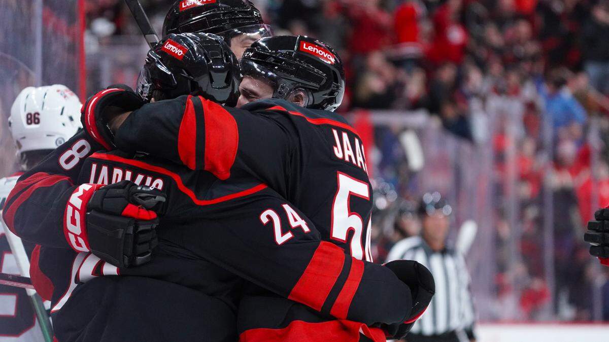 Carolina Hurricanes center Seth Jarvis (24) is congratulated by left wing Juha Jaaska (54) and defenseman Brent Burns (8) after his goal against the Chicago Blackhawks at Lenovo Center.