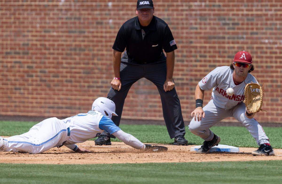 North Carolinas Vance Honeycutt (7) dives back to first base to beat the throw from Arkansas pitcher Connor Noland (13) to first baseman Robert Moore (1) in the third inning during the first game of their Super Regional series on Saturday, June 11, 2022 at Boshamer Stadium in Chapel Hill, N.C.