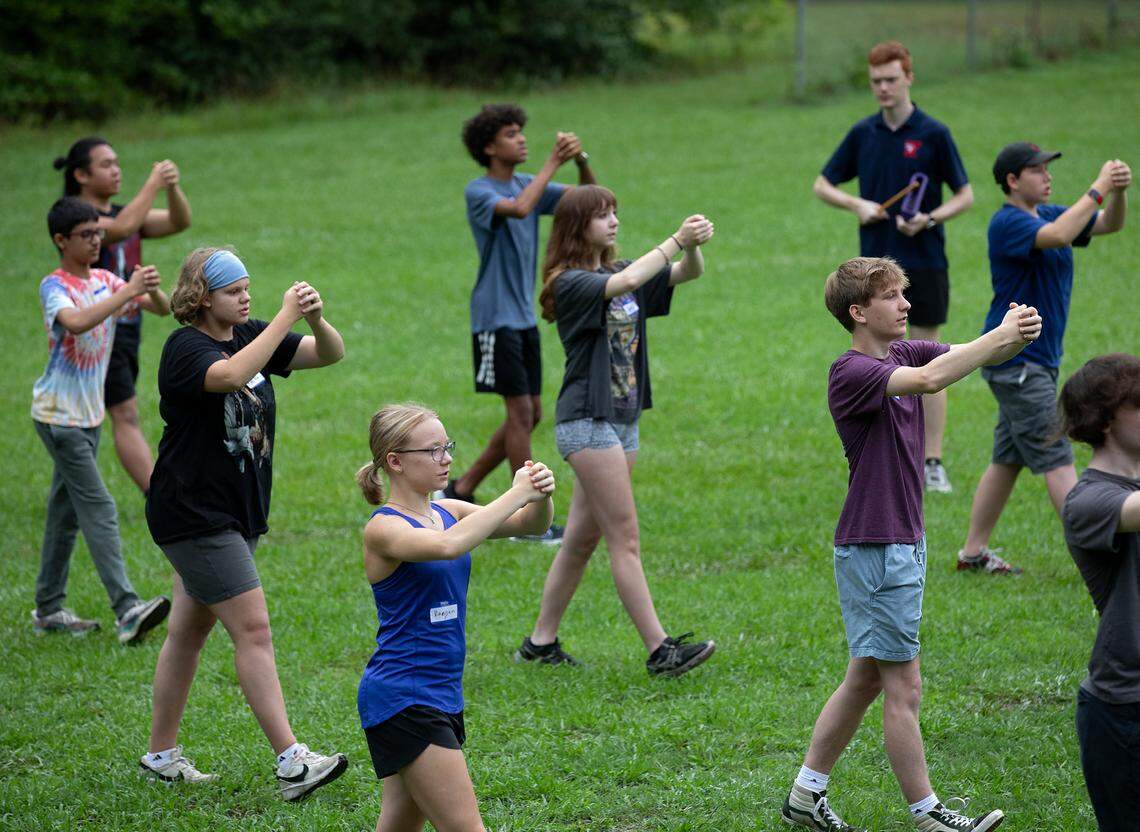 Students hold imaginary instruments while practicing marching technique during the first day of band camp at Jordan High School on Monday, July 22, 2024, in Durham, N.C.