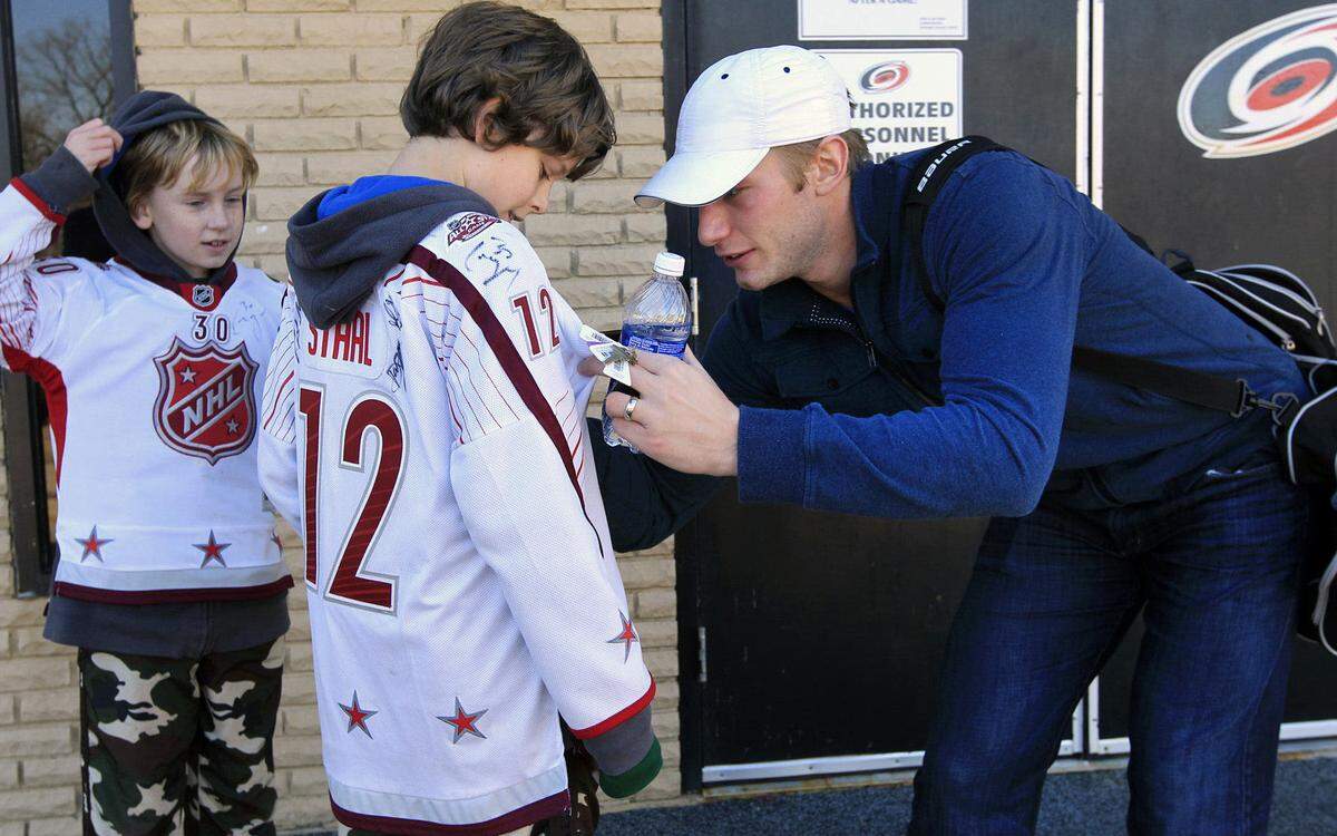 Canes fans Jake Miles, 9, left, and his brother Zac Miles, 12, center, get their All-Star sweaters signed by Jordan Staal after the Carolina Hurricanes worked out at Raleigh Center Ice in Raleigh, NC on Jan. 7, 2013.
