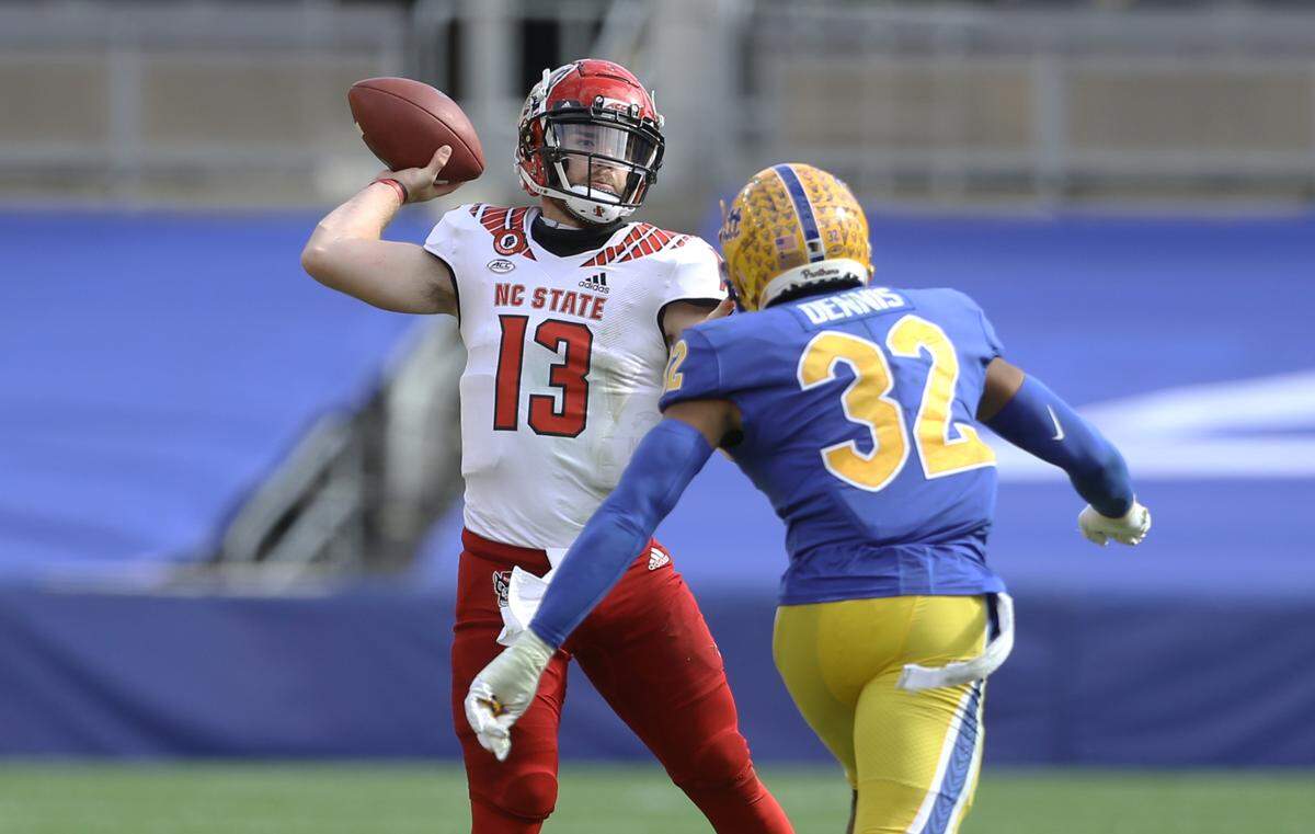 N.C. State quarterback Devin Leary (13) passes as Pittsburgh Panthers linebacker SirVocea Dennis (32) pressures him during their game at Heinz Field Saturday, Oct. 3, 2020.