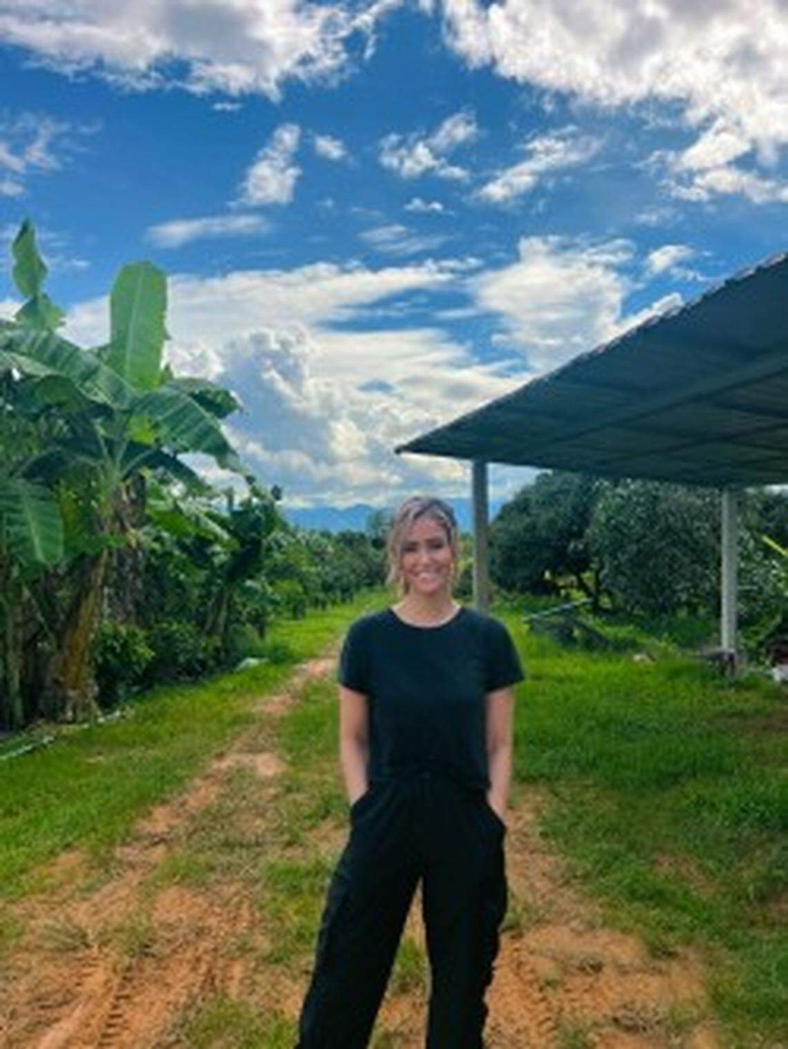 Hanna Yates stands in a field in Thailand where coffee is grown at Seed of Hope Coffee.